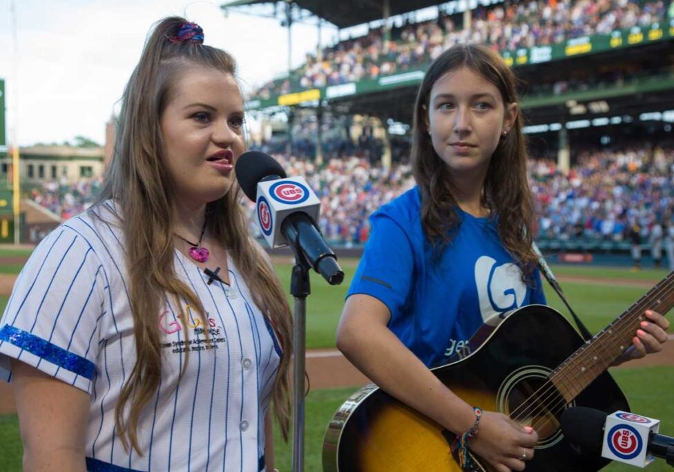GiGi Gianni sings National Anthem at Wrigley Field. To the right is Abby, from School of Rock in Barrington, playing the guitar.